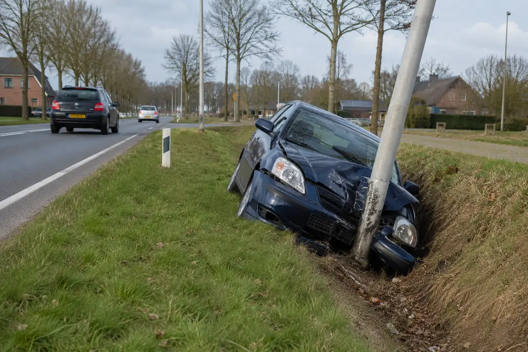Auto raakt lantaarnpaal en eindigt in droge sloot langs Rijksstraatweg